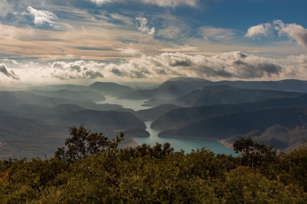 Pantano entre montañas con niebla y al amanecer.