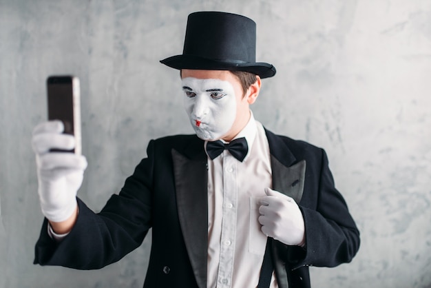 Pantomimeschauspieler mit Make-up-Maske macht Selfie