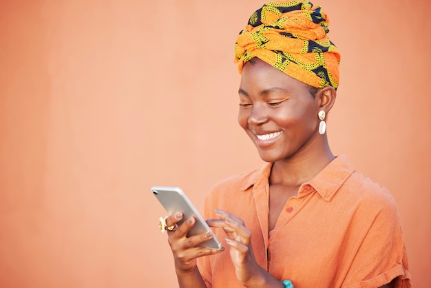 Pañuelo de cabeza de mujer negra y teléfono inteligente para comunicación de conexión y lectura en línea en el fondo del estudio Teléfono de dama jamaicana y sonrisa de niña con maqueta y maqueta de envoltura de cabeza tradicional