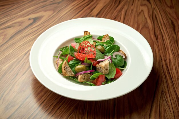 Panzanella-Salat mit Gemüse, Rucola, Parmesan und Brot in einem weißen Teller