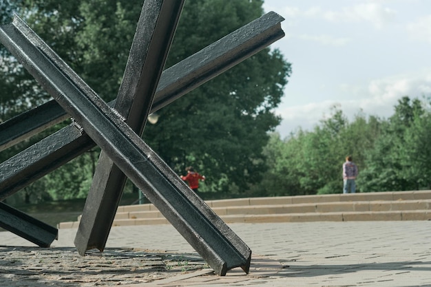 Panzerabwehr-Igel und Panzer in Nahaufnahme und friedlicher Hintergrund. Denkmal für alte Waffen in Nahaufnahme. Symbol für das Ende des Krieges. Alte Militärwaffen. Attrappe für den Angriffskrieg in der Ukraine