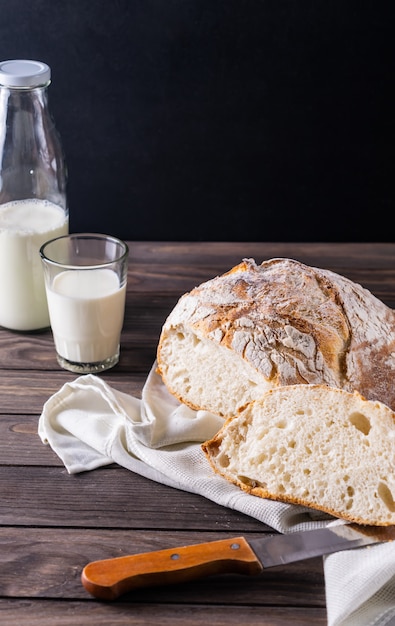 Pão acabado de cozer com leite composição rústica em um fundo preto