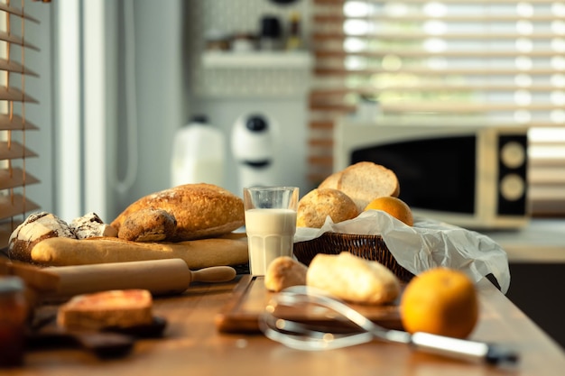 Pão acabado de cozer e copo de leite na mesa de madeira na cozinha Alimentação saudável e conceito de padaria tradicional