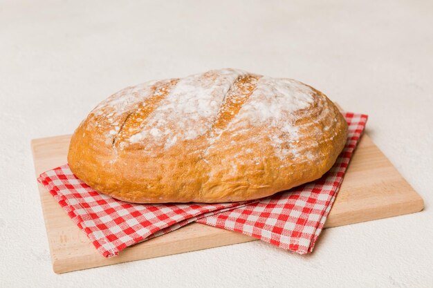 Pão acabado de cozer na tábua contra o fundo branco de madeira vista em perspectiva pão com espaço de cópia