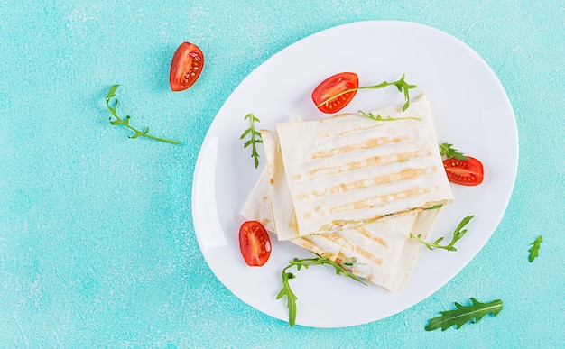 Pão achatado caseiro com presunto, ovos, queijo e tomate e ervas verdes