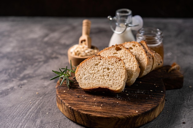 Pão artesanal baguete de trigo integral leite branco e mel em tábua de madeira rústica e mesa abstrata S