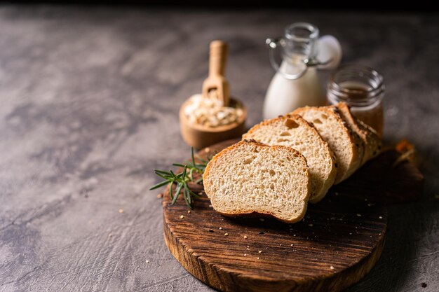 Pão artesanal baguete de trigo integral leite branco e mel em tábua de madeira rústica e mesa abstrata S