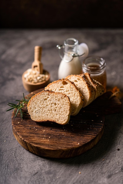 Pão artesanal baguete de trigo integral leite branco e mel em tábua de madeira rústica e mesa abstrata S