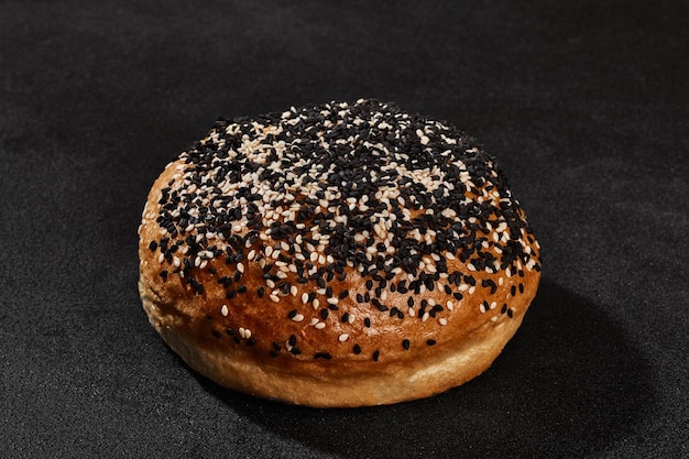 Pão assado palatável fresco polvilhado com sementes de gergelim contra fundo preto com espaço de cópia Cozinha rural ou padaria Closeup