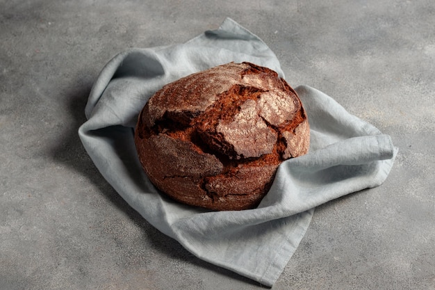 Pão ázimo escuro artesanal tostado em fundo de pedra cinza com guardanapo de linho azul