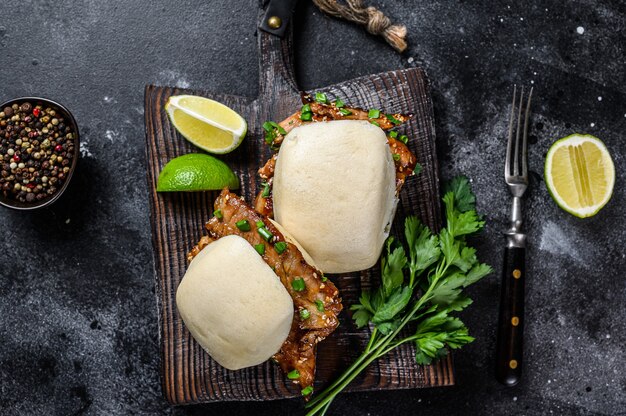 Pão bao cozido no vapor com barriga de porco e legumes. fundo preto. vista do topo.