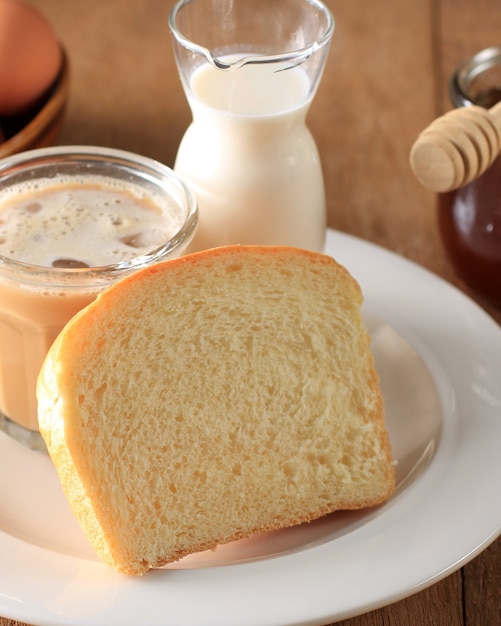 Pão branco de pão branco fatiado fresco assado japonês, popular como pão de leite de Hokaido, servido com mel, leite e ovo no café da manhã. Bakery Brown Concept