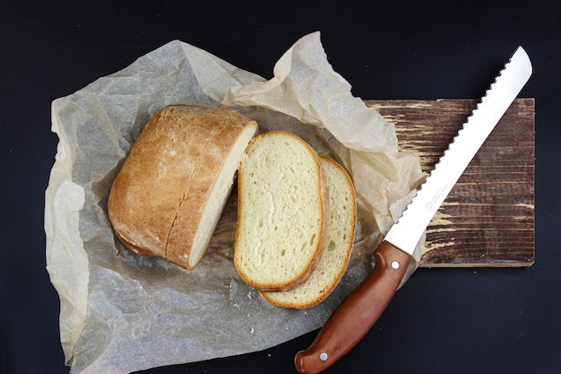 Pão branco e faca na tábua de madeira Pão duro e faca de pão velha na tábua de cortar