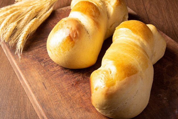 Pão caseiro, dois lindos pães caseiros na madeira e um galho de trigo.