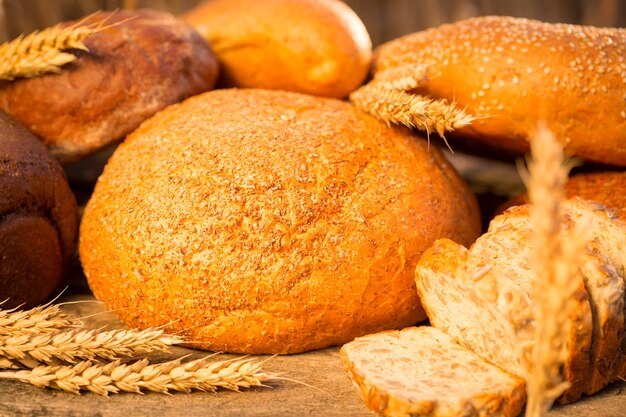 Pão caseiro e trigo na mesa de madeira no campo de outono