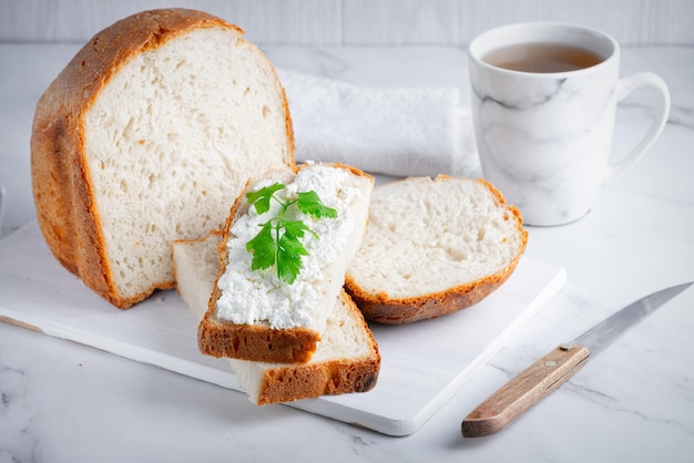 Pão caseiro em uma tábua de madeira com requeijão