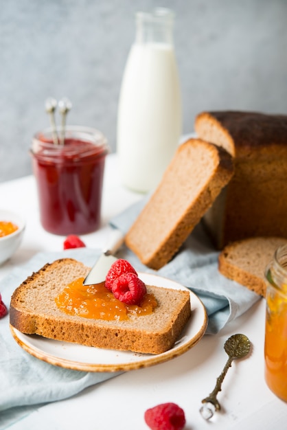 Pão caseiro fresco com geléia e leite, comida caseira simples, fundo claro