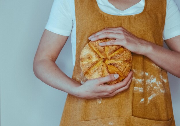 Pão caseiro recém-feito tirado do forno, crosta deliciosa, mãos femininas segurando pão.