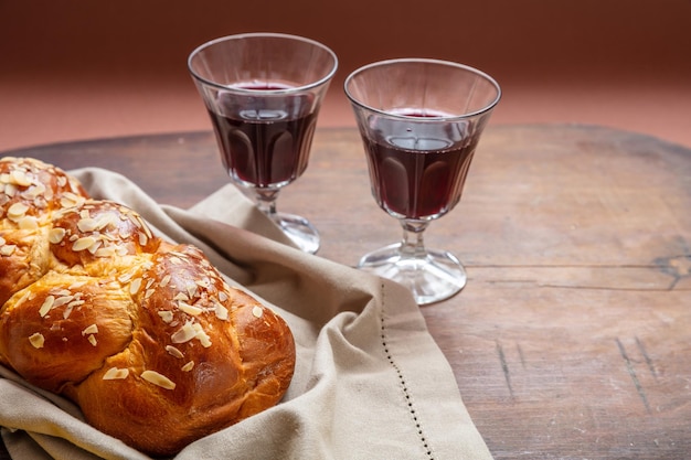 Pão challah com dois copos de vinho tinto no espaço de cópia de mesa de madeira