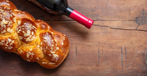 Pão Challah com uma garrafa de vinho tinto no espaço de cópia de mesa de madeira