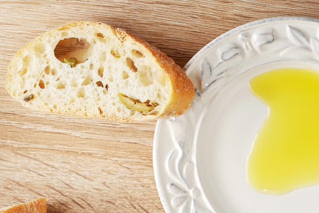 Pão ciabatta com azeitonas e um prato de azeite amarelo