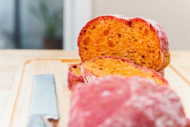 Pão ciabatta italiano de beterraba caseiro cortado em fatias na placa de madeira