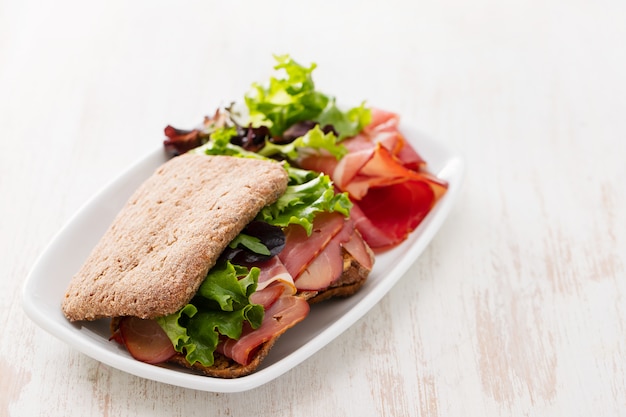 Pão com carne defumada e salada no prato