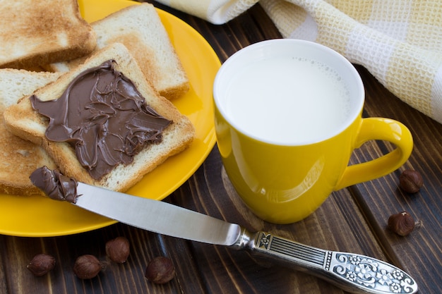 Pão com creme de chocolate e leite na xícara amarela