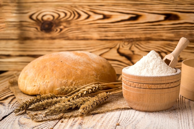 Foto pão com espigas de farinha de trigo e grãos na mesa de madeira conceito de agricultura e colheita