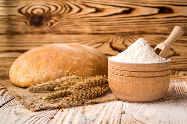 Pão com espigas de farinha de trigo e grãos na mesa de madeira Conceito de agricultura e colheita