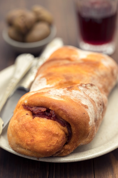 Pão com linguiça defumada no prato e vinho tinto