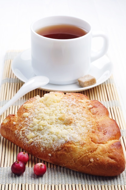 Pão com xícara de chá e cranberry na mesa branca