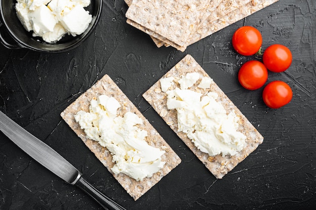 Pão crocante de centeio fresco com cream cheese definido, no fundo da mesa de pedra escura escura, vista superior plana lay