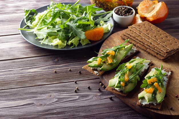 Pão crocante integral com queijo, folhas de rúcula, tangerina e salada verde fresca