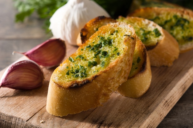 Pão de alho fatia e ingredientes na mesa de madeira.