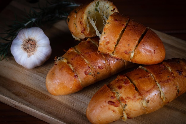 Foto pão de alho recheado com queijo em uma tábua de corte em uma mesa de madeira pão rústico feito à mão