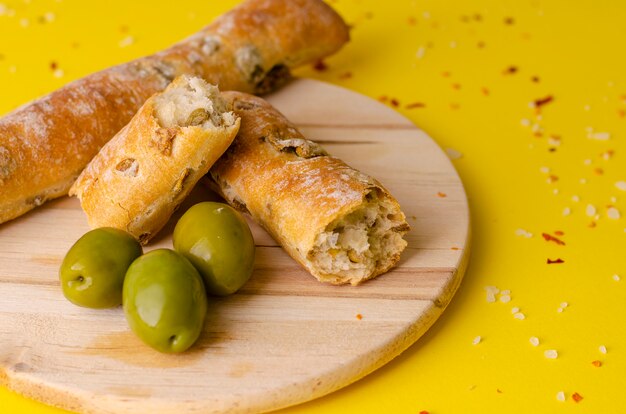 Pão de azeitona rústico italiano varas em fundo amarelo com espaço de cópia