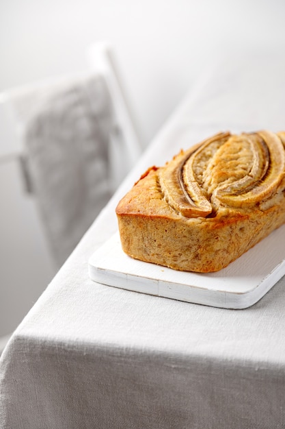 Pão de banana caseiro em uma placa de madeira sobre uma mesa com uma toalha de mesa