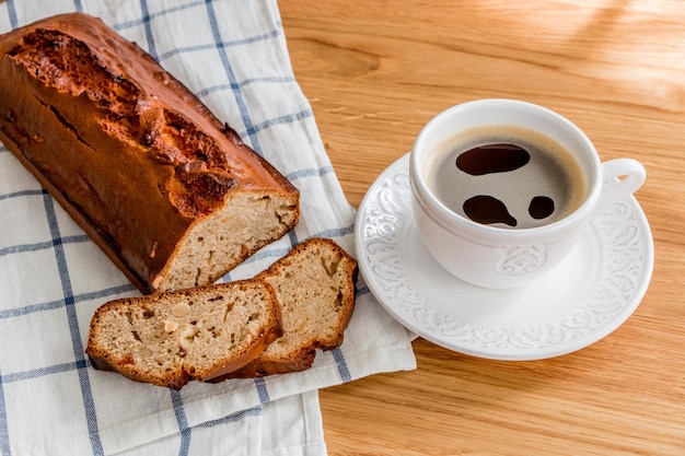 Pão de banana recém-assado e uma xícara de café em uma mesa de madeira