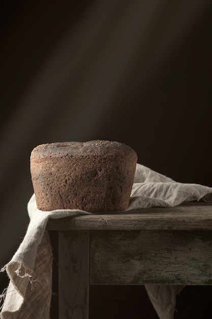 Pão de centeio cozido em um guardanapo de linho cinza, velha mesa de madeira