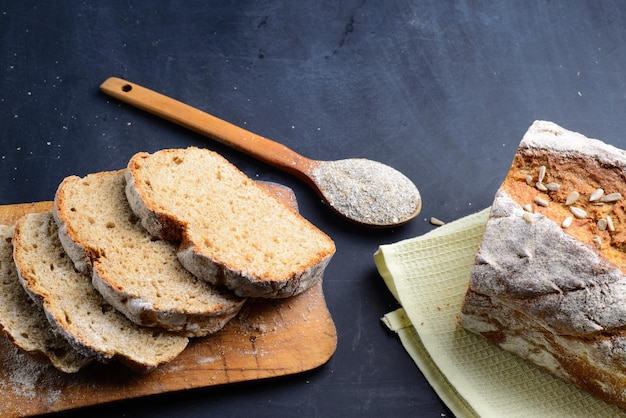 Pão de centeio fatiado em uma tábua Em uma mesa preta Vista superior