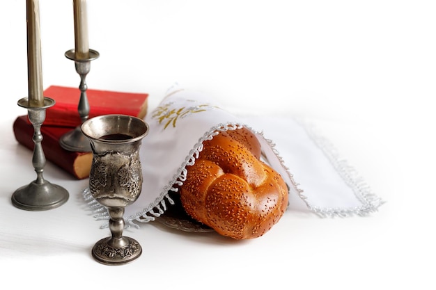 Pão de chalá coberto com um guardanapo especial vinho de shabbat e velas em fundo branco Ritual de shabat judaico tradicional Shabbat Shalom