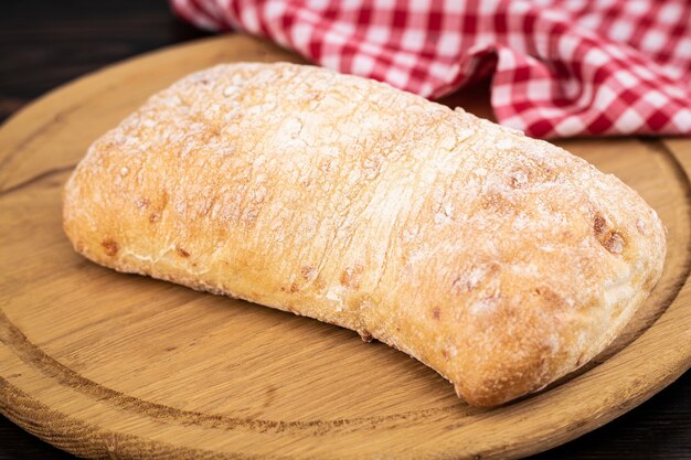 Pão de ciabatta em uma tábua de cortar na mesa de madeira escura