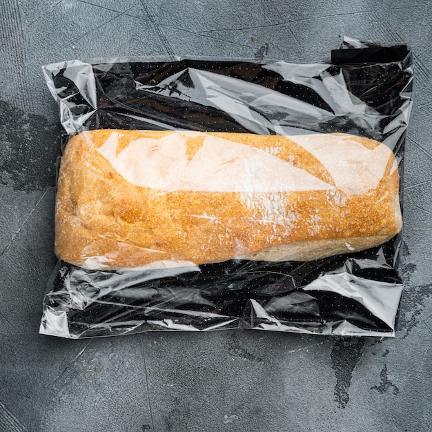 Pão de ciabatta integral artesanal recém-assado em uma sacola de mercado, em fundo cinza, vista de cima plana lay