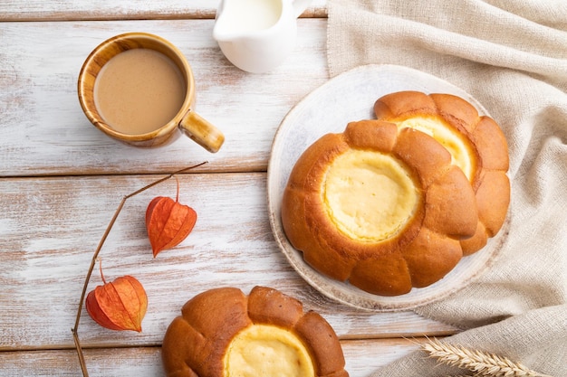 Pão de creme de leite com uma xícara de café em uma vista superior de fundo branco de madeira