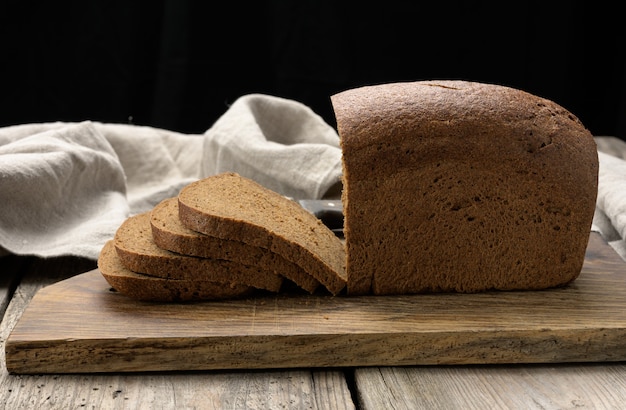 Pão de farinha de centeio assado em fatias retangulares no tabuleiro marrom, comida saudável