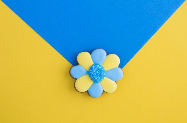 Pão de gengibre em forma de flor com pétala azul e amarela no fundo coloridoVista superior Copiar espaço