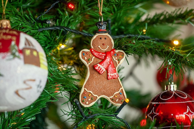 Pão de gengibre pendurado na árvore de natal com bolas e luzes