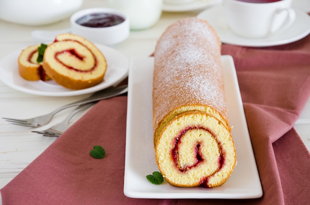 Foto pão de ló caseiro com geleia de framboesa em um prato branco com uma xícara de chá de frutas silvestres perfumado