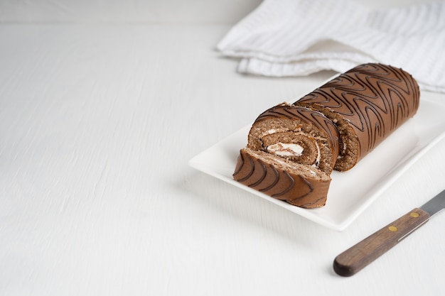 Pão de ló ou pão doce com recheio de creme fatiado no prato com uma faca no fundo de madeira